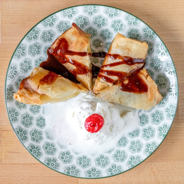 Plum Vietnamese Restaurant's fried banana dessert with chocolate drizzle, vanilla ice cream, and a cherry.