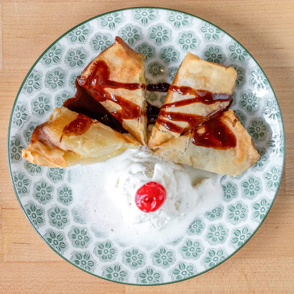 Plum Vietnamese Restaurant's fried banana dessert with chocolate drizzle, vanilla ice cream, and a cherry.