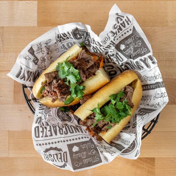 Two Plum Vietnamese Restaurant banh mi sandwiches with beef and cilantro in a basket.