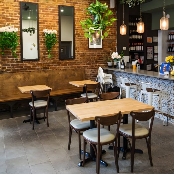 Interior of Plum Vietnamese Restaurant with brick walls, wooden tables, and a patterned bar.