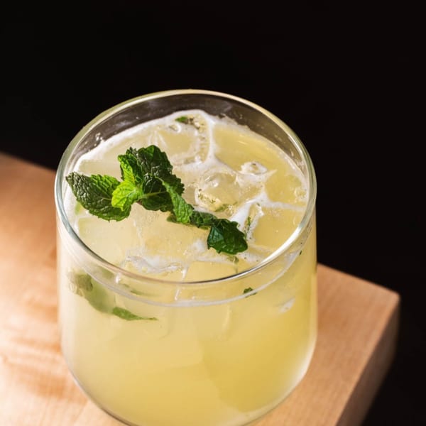 Refreshing iced Vietnamese lemonade with mint garnish, served in a glass on a wooden surface.