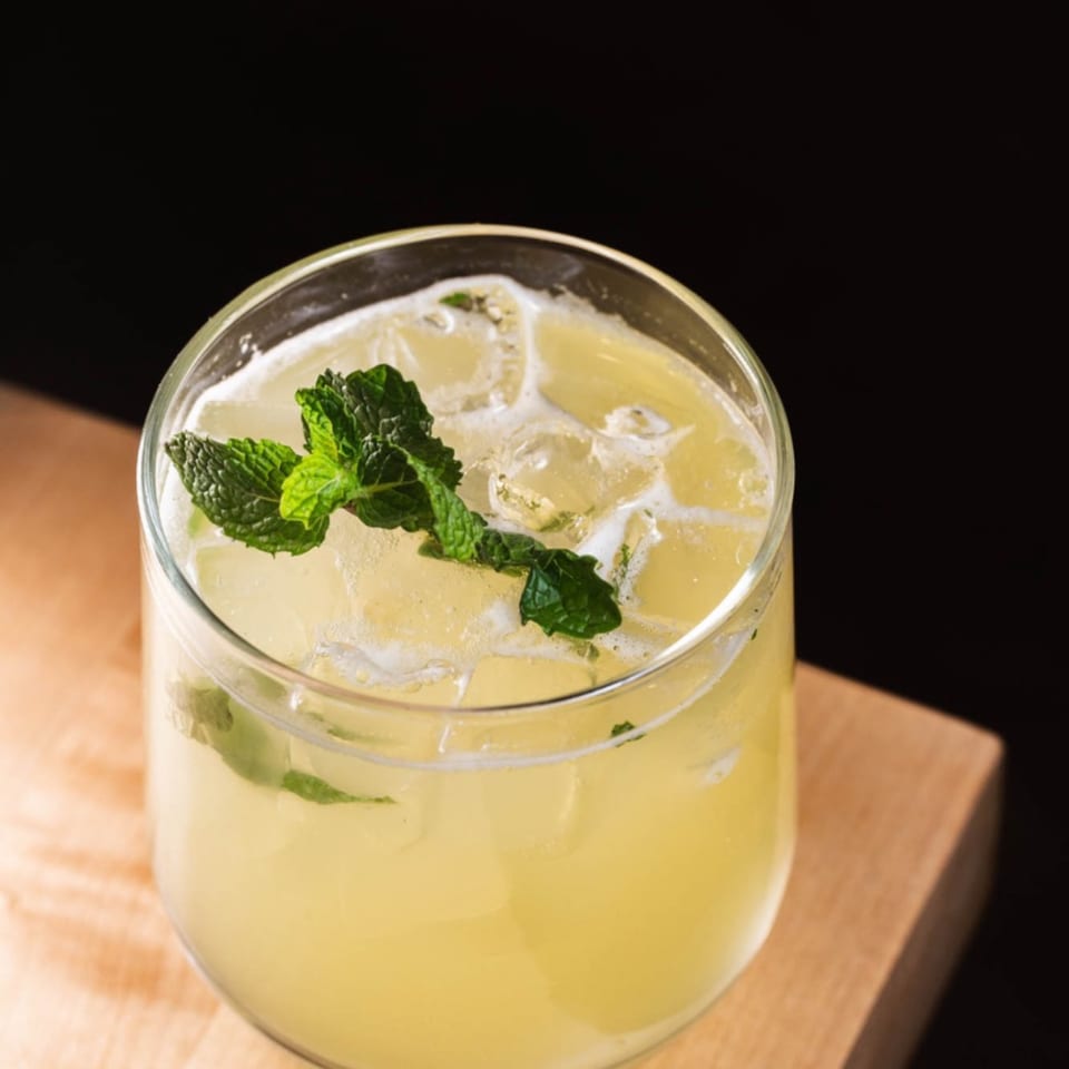 Refreshing iced Vietnamese lemonade with mint garnish, served in a glass on a wooden surface.