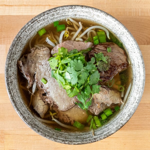 A bowl of Plum Vietnamese Restaurant's pho with beef, bean sprouts, and cilantro.