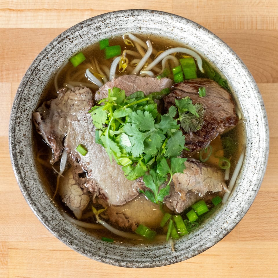 A bowl of Plum Vietnamese Restaurant's pho with beef, bean sprouts, and cilantro.