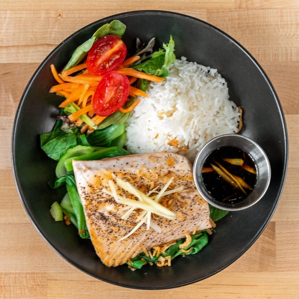 Plum Vietnamese Restaurant's salmon dish with rice, bok choy, salad, and a side of sauce.